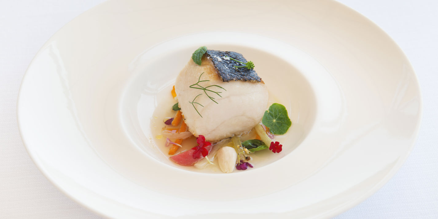 Roasted amberjack with cooked vegetable salad, almonds and tomato water